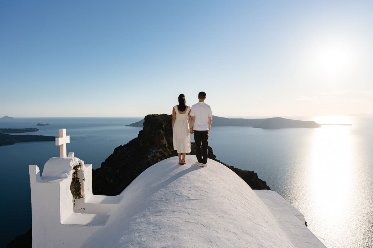 Couple on the roof of the Agios Georgios chapel below Skaros Rock, Imerovigli, at sunset
