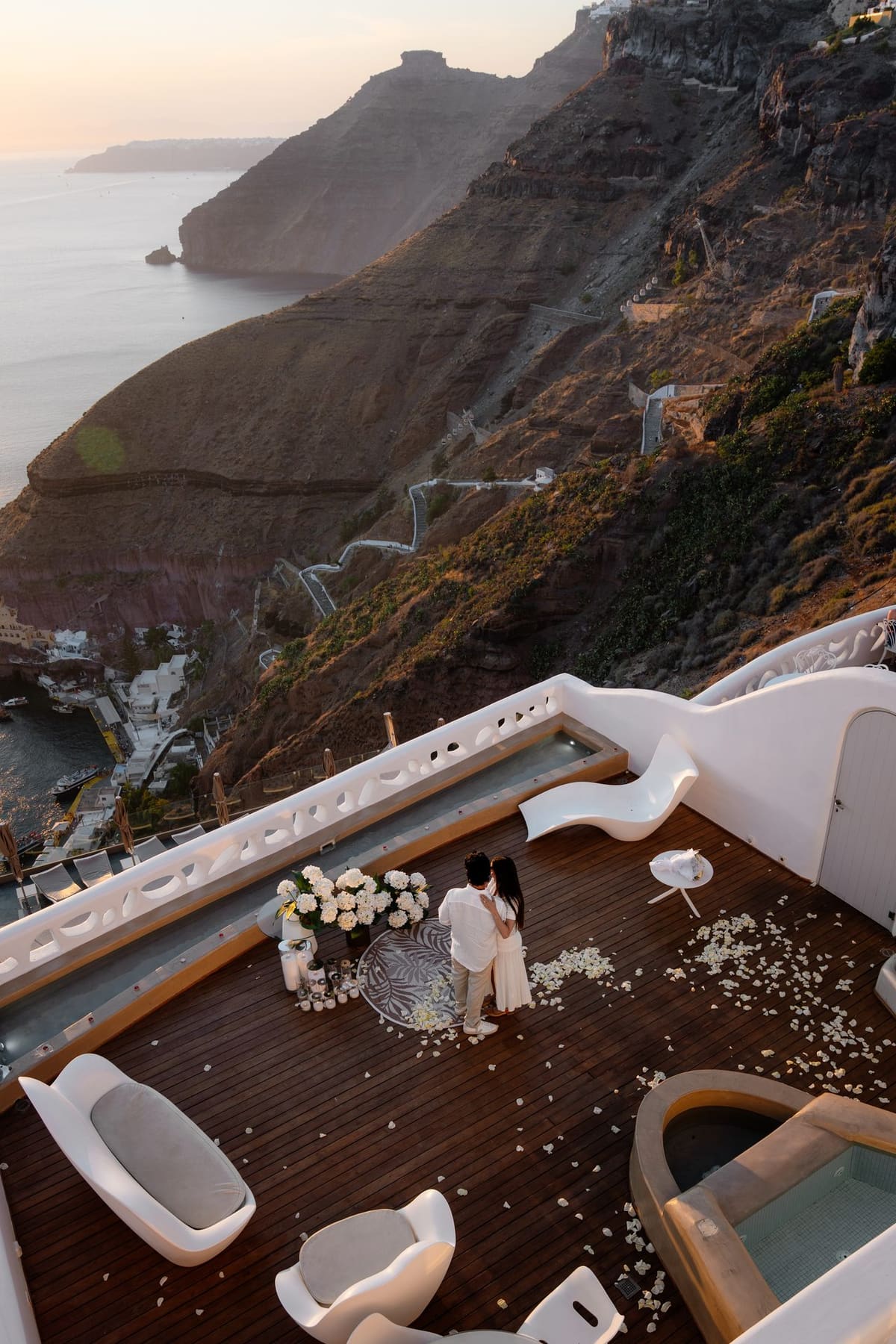 Couple celebrating their engagement on a terrace above the Fira caldera at golden hour
