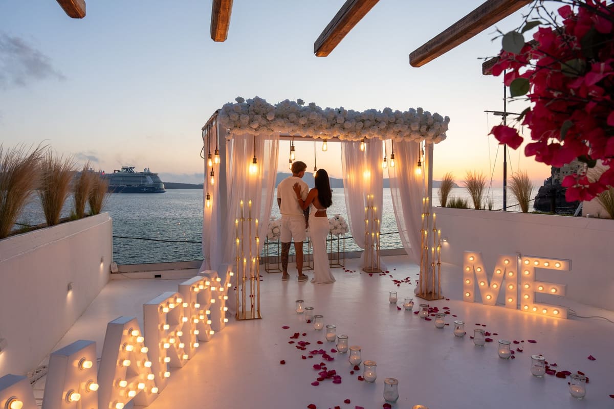 The proposal pergola glowing at blue hour with a cruise ship on the caldera, Santorini