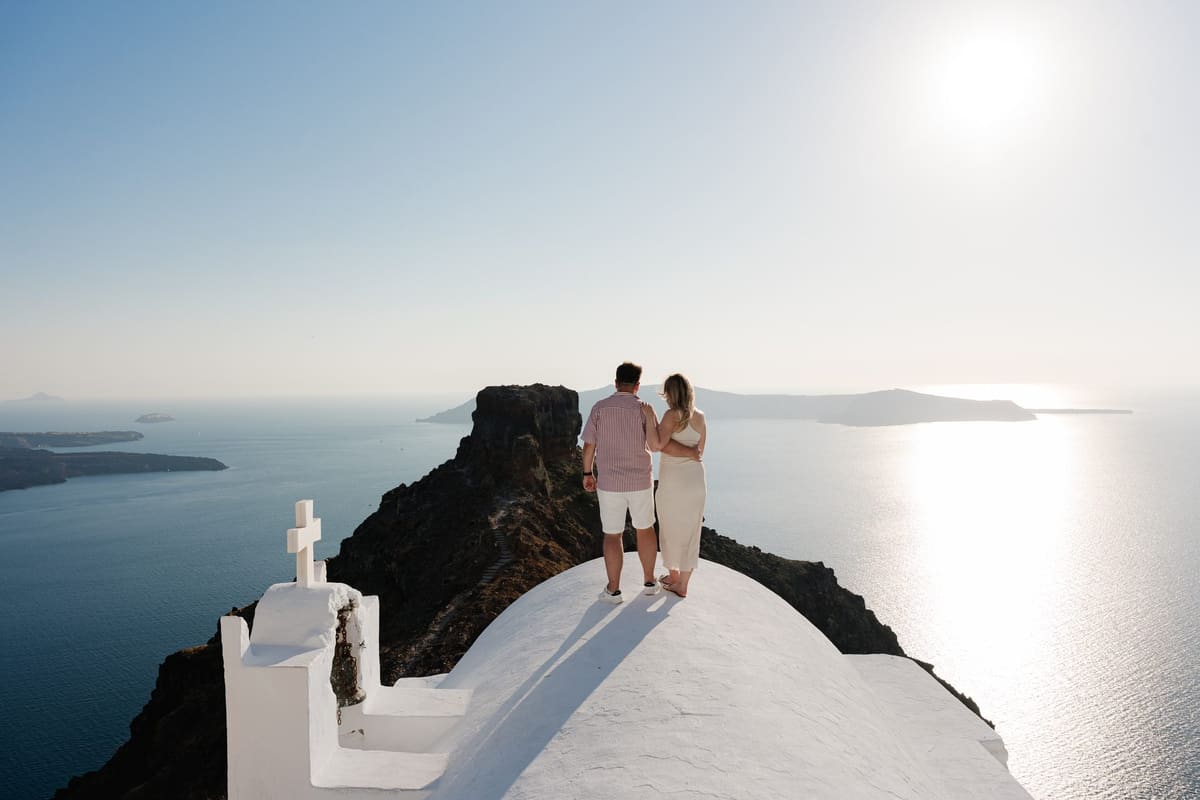 Couple on the roof of the Agios Georgios chapel with Skaros Rock and the sea shining