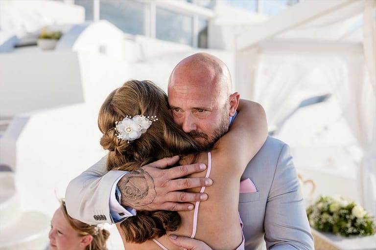 Groom hugging a guest with tears after the ceremony at a Santorini caldera venue